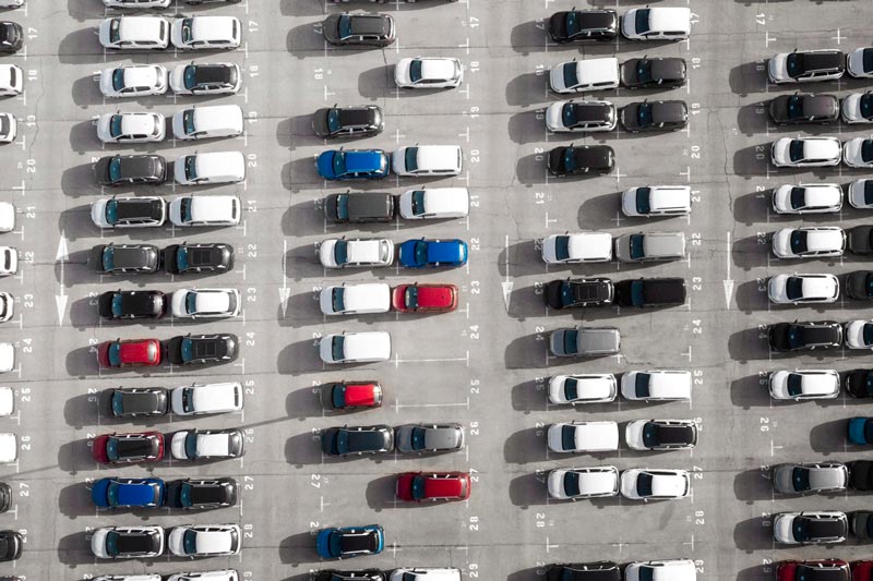 Vogelperspektive auf einen großen Parkplatz bei Gebrauchtwagen Ankauf Ulm, der mit Reihen weißer Autos gefüllt ist.